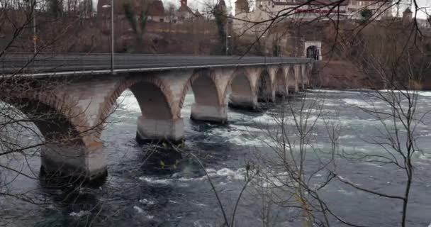 スイスのライン滝の急流近くの滝 川を渡る古い鉄道橋 寒い秋の曇りの天気 — ストック動画