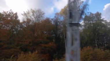 Yavaş çekimde tren yolculuğu orman manzarası sonbahar ağaçları renkli yapraklarla yan yana.