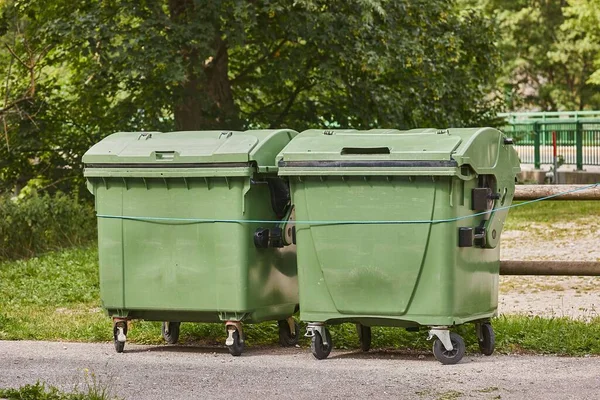 在绿色街道上堆放都市废物的垃圾箱 — 图库照片