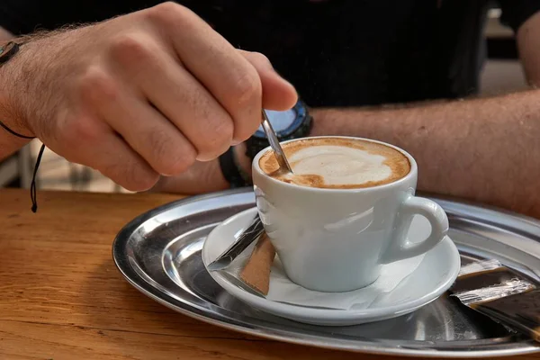 在咖啡店里喝咖啡时 男人在卡布奇诺身上划了条带 — 图库照片
