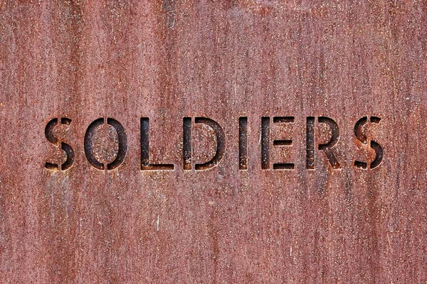 Palavra Soldados Cortados Uma Superfície Metal Enferrujado — Fotografia de Stock