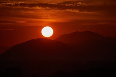 Karanlık dramatik bulutlar ve tepeler arasında gün batımı