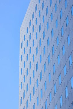 Mavi gökyüzünü yansıtan pencereli basit ofis binası detayı