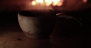 Laponya 'dan geleneksel kuksa, şöminenin yanında yükselen sıcak çay buharı ahşap bir kulübede oturur.
