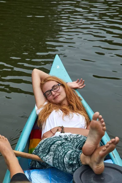 ボートの前に横たわる夏の日差しを楽しむ川の若い女性のカヌー — ストック写真