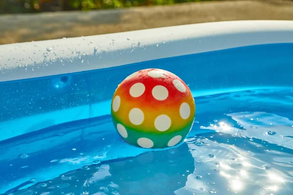夏の日差しの中で庭の膨脹可能な子猫プールでのゴムボール 斑点のあるプラスチックボール — ストック写真