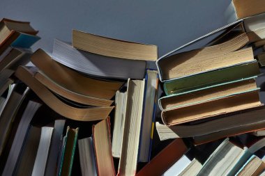 Tavan arasında dramatik loş ışıkta kitap yığını, arka plan kitap duvarı oluşturur.