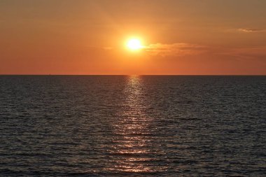 Sonsuz denizin ufuklarında batan güneş, kumsalda gün batımı