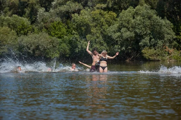 若い人たちは暑い夏休みに川で冷却し 男と女の子のグループの写真は 水をはね — ストック写真