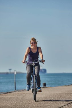 Hoek Van Holland 'da deniz kıyısında bisiklet süren bir kadın.