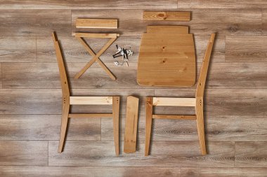 Tahta sandalye monte edilmeye hazır, mobilya parçaları boks açıldıktan sonra serilmiş.