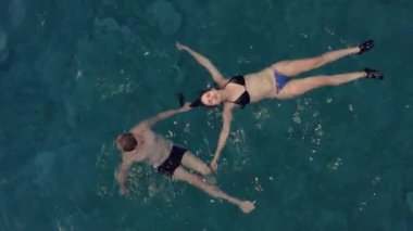 Denizde yüzen insanlar, derin mavi sular, yukarıdan insansız hava aracı manzarası.