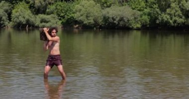 Akan bir nehirde ağır bir kütük atan adam.