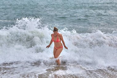 Sahilde büyük dalgalardan kaçan bir kadın