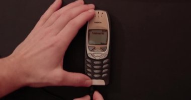 Budapeşte, Macaristan - 10 Ocak 2022: Klasik Nokia 6310i cep telefonu şarjı. Şarj kablosuna bağlı eski model cep telefonu çalışma aygıtı