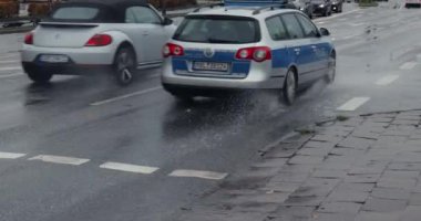 Rostock, Almanya - 21 Ekim 2021: Şiddetli yağmurdan sonra birikintiler, şehir caddesinde su sıçratan arabalar