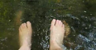 Serin bir dağ deresinde çıplak ayaklar, yaz yürüyüşü için dinlenme, 4K 'da 60 fps görüntü.