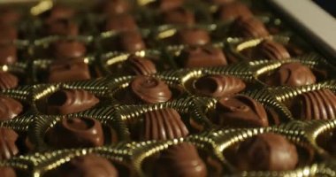 Bir kutu çikolatalı bonbon şekeri yakın plan dönen bir masanın üzerinde.