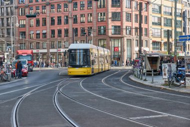 Berlin, Almanya - 21 Ekim 2023: Tramvaylar bir istasyona varıyor, insanlar güneşli sonbahar havasında sokaklara dökülüyor