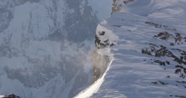 Şiddetli rüzgarda kar kristalleri savruldu ve yüksek bir dağ sırtında kar fırtınası Alplerdeki keskin uçurumlar