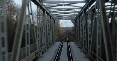 Tren yolculuğu eski bir köprüyü geçiyor, arkadan manzaralı.