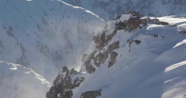 Şiddetli rüzgarda kar kristalleri savruldu ve yüksek bir dağ sırtında kar fırtınası Alplerdeki keskin uçurumlar