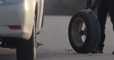Arabanın tekerleği değişiyor, yol kenarında yedek lastik var.