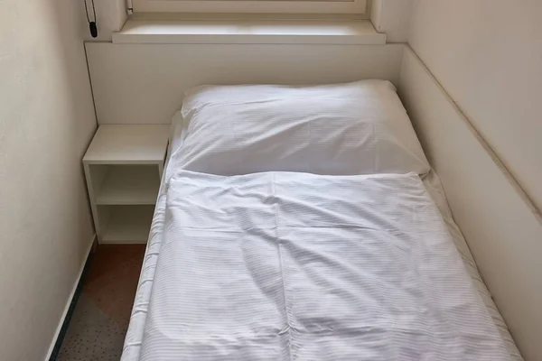Bed made with sheets in a simple hostel dormitory