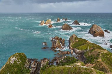 Nugget Point 'te kıyı manzarası. Kıyı şeridinde azgın deniz taşları aşınıyor.