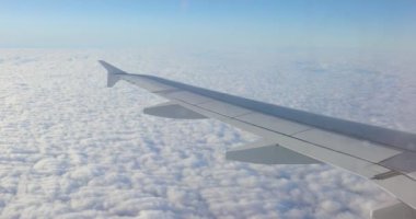Uçak lekeli pencereden, bulutların üstündeki parlak güneş ışığı kanadından görüntü