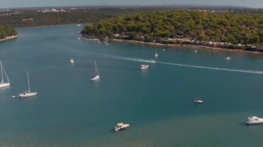 Hırvatistan 'ın Pula kentinin Uvala kenti yakınlarındaki Akdeniz kıyısındaki bir körfezin havadan görüntüsü. Tekneler yazın denize açılıyor, güneşli bir hava.