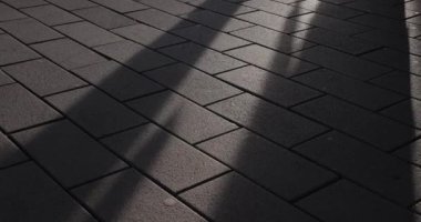 Ağır çekimde geçen insanların gölgeleriyle asfalt taşlar.