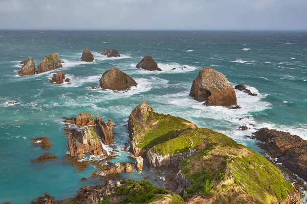 Nugget Point 'te kıyı manzarası. Kıyı şeridinde azgın deniz taşları aşınıyor.