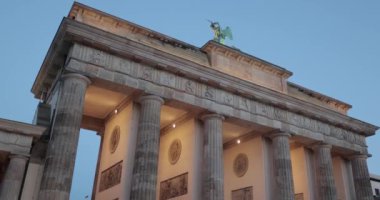 Berlin, Almanya - 22 Ekim 2022: Brandenburg Kapısı, Berlin 'in tarihi simgesi. Anıt akşam manzarası, mavi saatte aşağı doğru eğilen kamera.