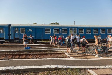 Tiszafved, Macaristan - 18 Ağustos 2022: Yazın istasyonda tren bekleyen bir grup insan, bazıları bisikletli