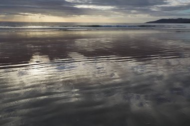 Deniz koyundaki kumsal, sakin su yansıması.