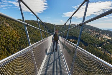 Walking on a suspension footbridge between mountain ridges, Skybridge 721, longest in the world, Czech Republic clipart