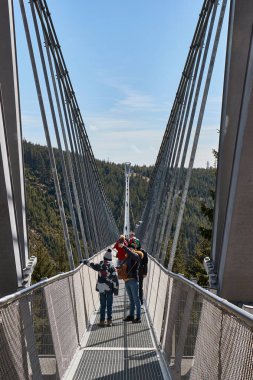 Dolni Morava, Czechia - March 30, 2024: Skybridge 721, longest suspension footbridge in the world, people crossing and enjoying the view of surrounding mountains clipart