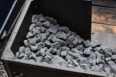 Siyah kömür, buharlı bir lokomotifi takip eden vagondaki büyük bir depoyu taşır.