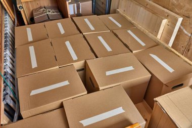 Taşınan evler için paketlenmiş karton kutular, boş etiketler, bir minibüsün arkasına yüklenmiş.
