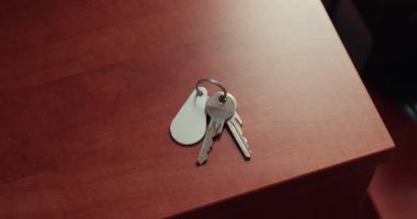 Oda anahtarları ahşap bir masada yatıyor, anahtarları alıp gidiyor ve onları alıyor.