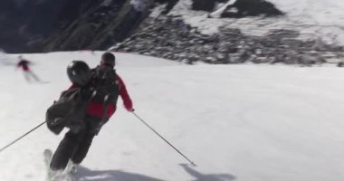 Alplerde kayak yaparken, erkek kayakçı hızla alçalıyor, dinamik çekim takip ediyor