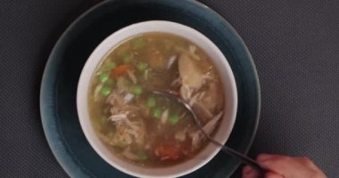 Masada tavuk ve sebzeli et çorbası, kaşıkla sıcak yemek.