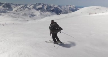 Alplerde kayak yaparken, erkek kayakçı hızla alçalıyor, dinamik çekim takip ediyor