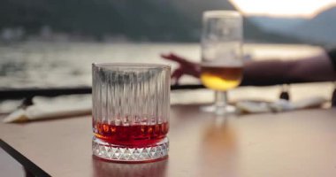 Deniz kenarındaki bir restoranda içki içmek, Negroni kokteyli ve masada bir bardak bira içmek..