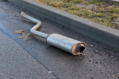 Rezonatörlü araba egzoz borusu düştü ve yol kenarında hasar gördü.,