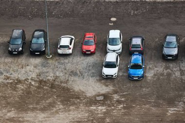Çakıl taşları ve toprak alana park etmiş arabalar, fabrika için asfaltsız otopark.