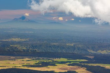 Tongariro Ulusal Parkı, Yeni Zelanda 'dan bakıldığında, tepeleri ve arka planda Taranaki Dağı olan dramatik bulutlu bir manzara.