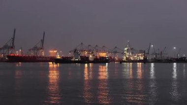 Rotterdam, Hollanda - 12 Şubat 2023: Kargo konteyner terminali gece Rotterdam limanında, Maasvlakte limanında vinçlerle dolu büyük konteyner gemileri