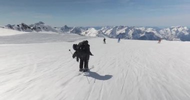 Alplerde kayak yaparken, erkek kayakçı hızla alçalıyor, dinamik çekim takip ediyor